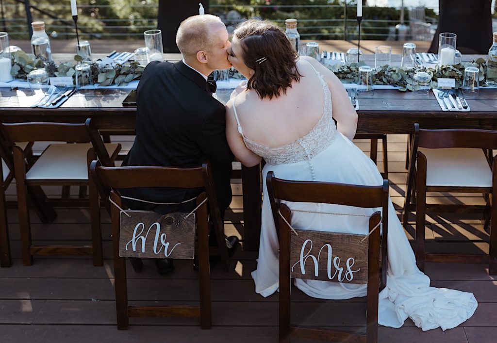Bride and groom kiss seated at reception table of Wisconsin elopement