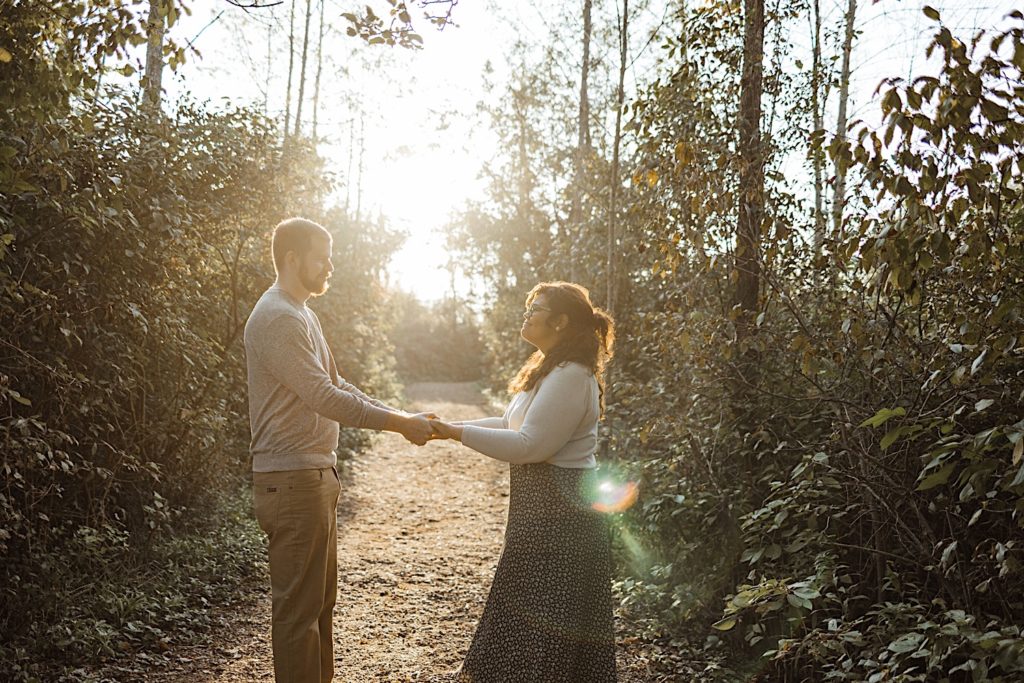Couple hold hands for engagement photo in park near Milwaukee