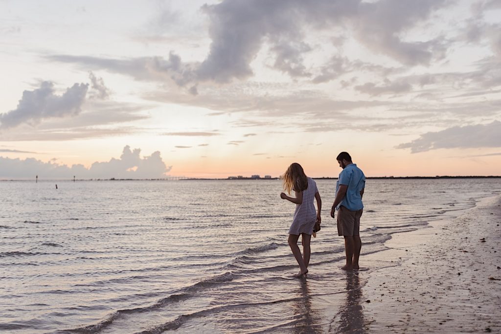 Couple walk along beach water, photographed by destination photographer
