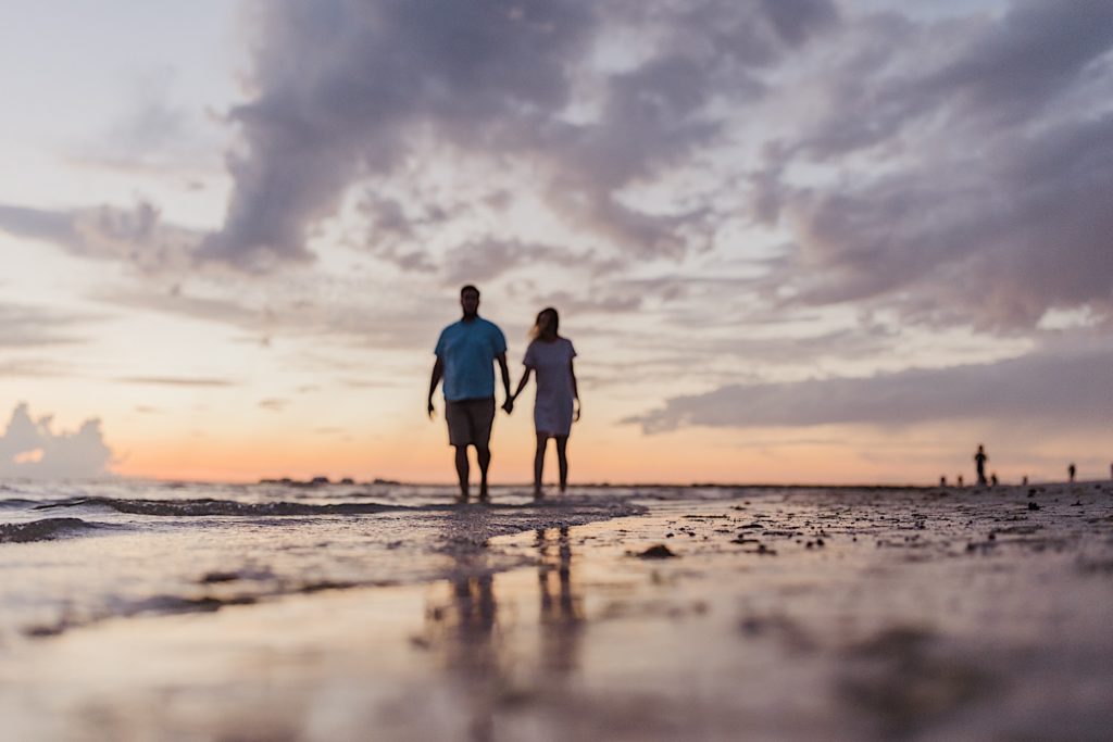 Couple walking along the beach at sunset, photographed by destination photographer