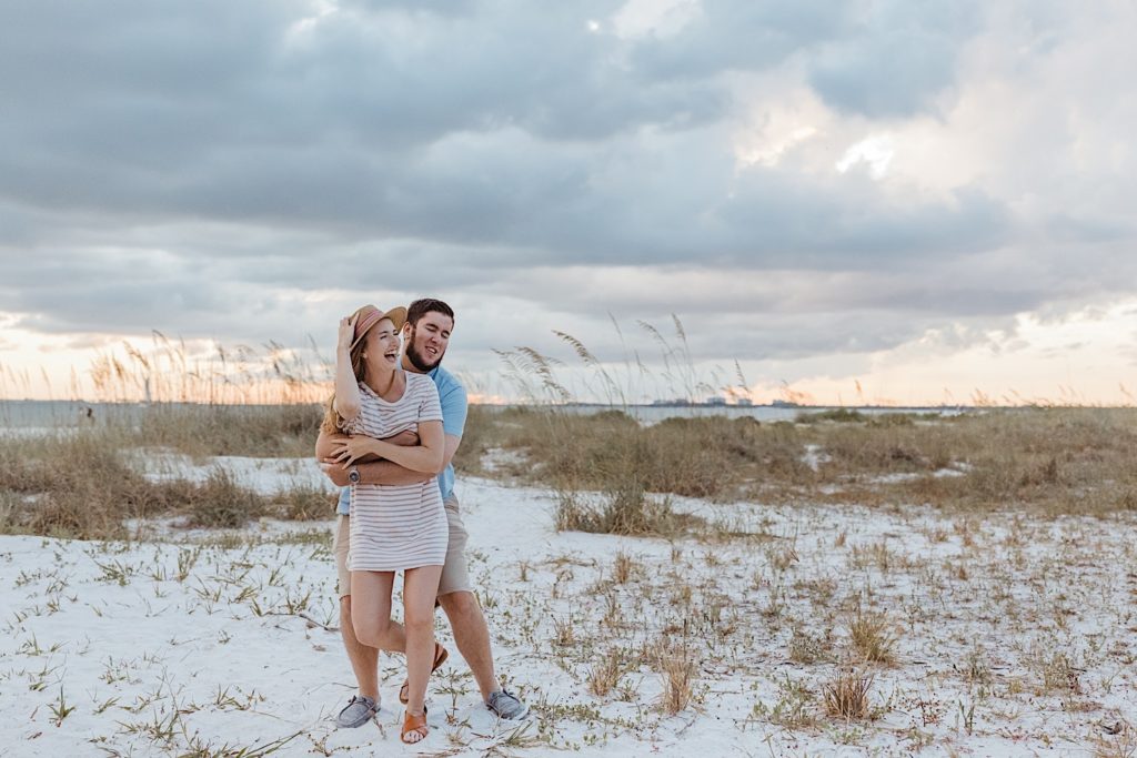 Couple hug and laugh on the beach, photographed by destination photographer