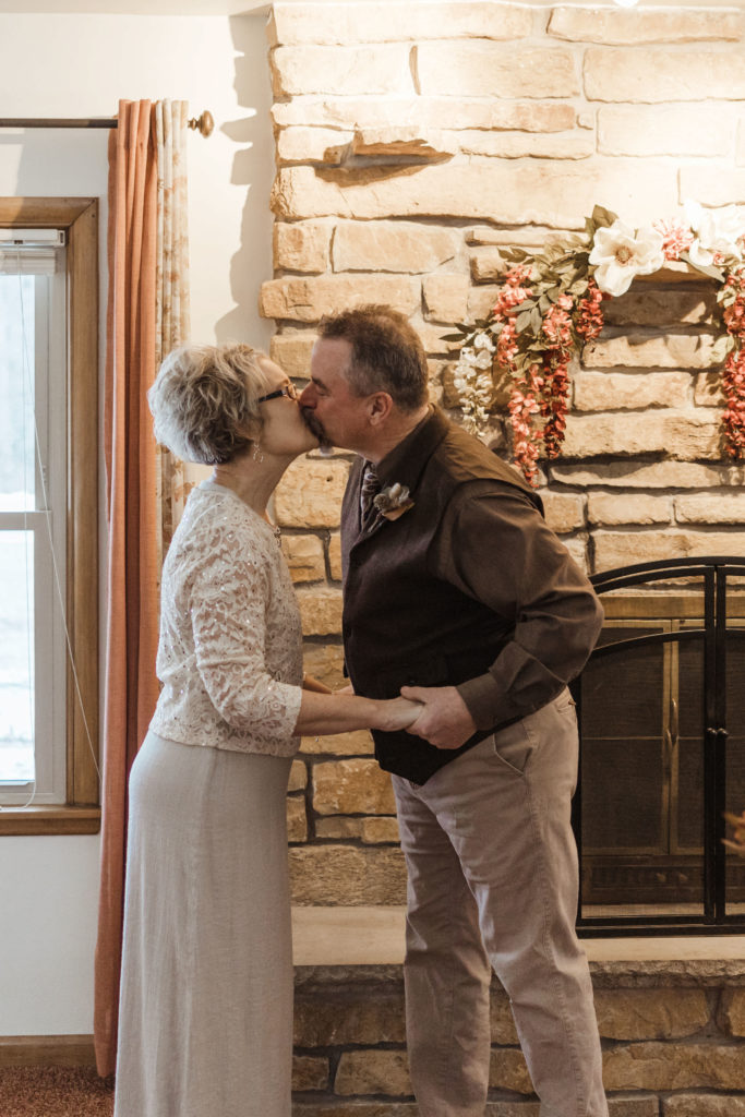 Bride and groom kiss during their in home wedding reception