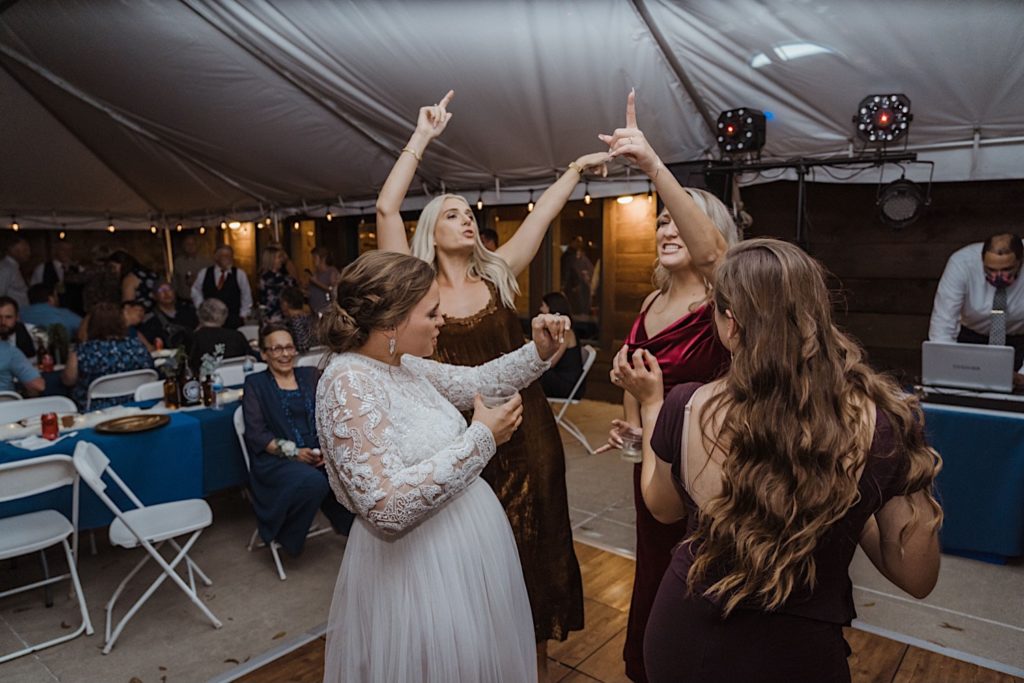 Bride and guests dance under a tent during wedding reception