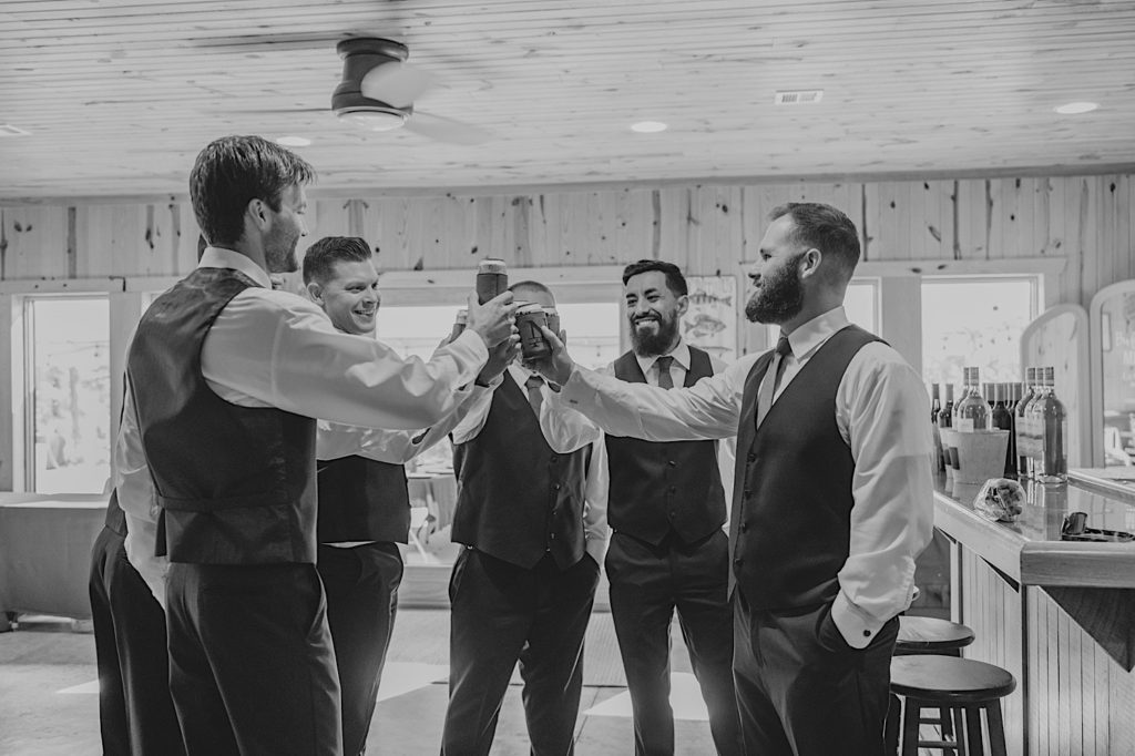 Black and white photo of groom and groomsmen toasting to their day